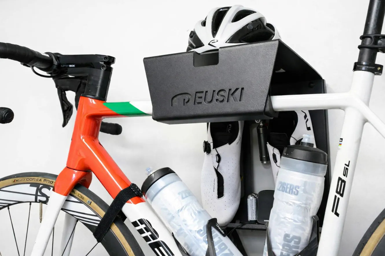 Soporte de pared para bicis color negro, casco, zapatillas y gafas colocadas, fondo blanco
