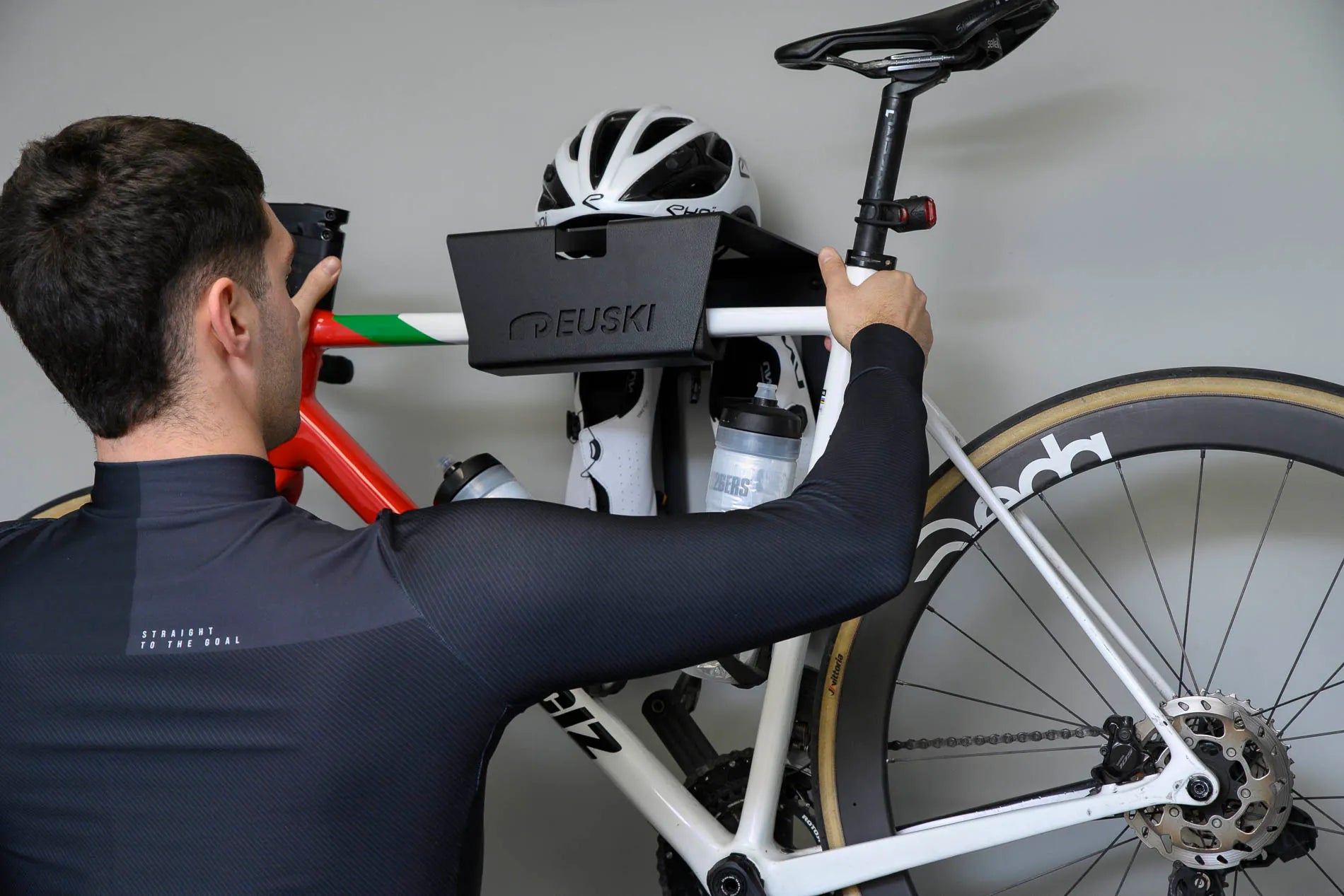 Ciclista colocando la bici en el soporte de pared para bicis instalado en el salón